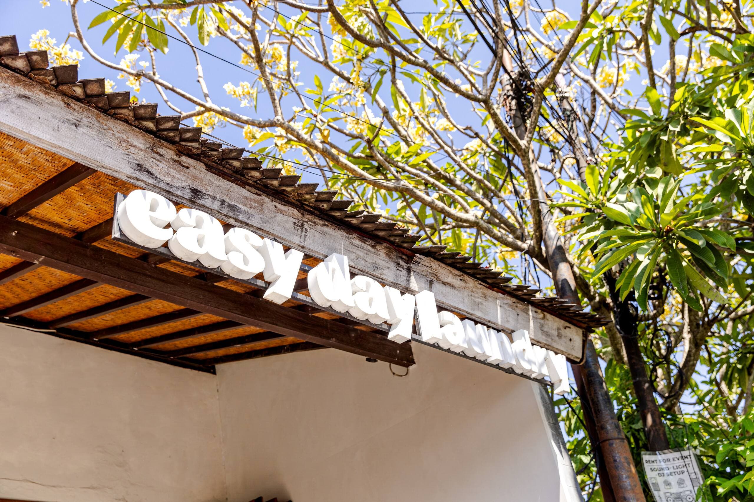 Easy Day Laundry shop sign under a frangipani tree in Seminyak