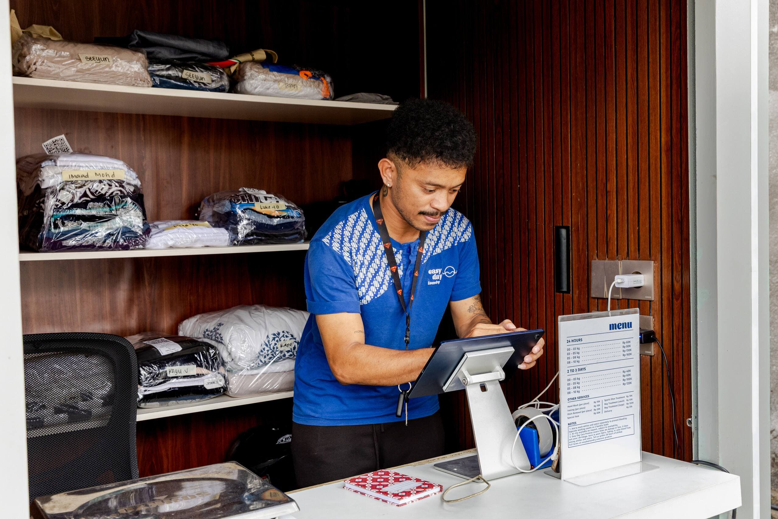 Easy Day Laundry team member logging an order on the tablet at the drop-off booth