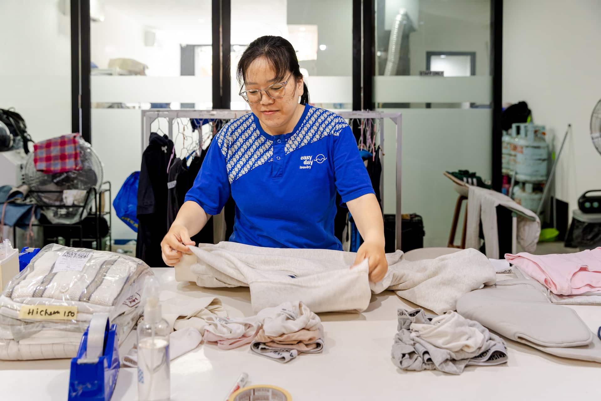 Easy Day Laundry team member folding a sweatshirt at the finishing table