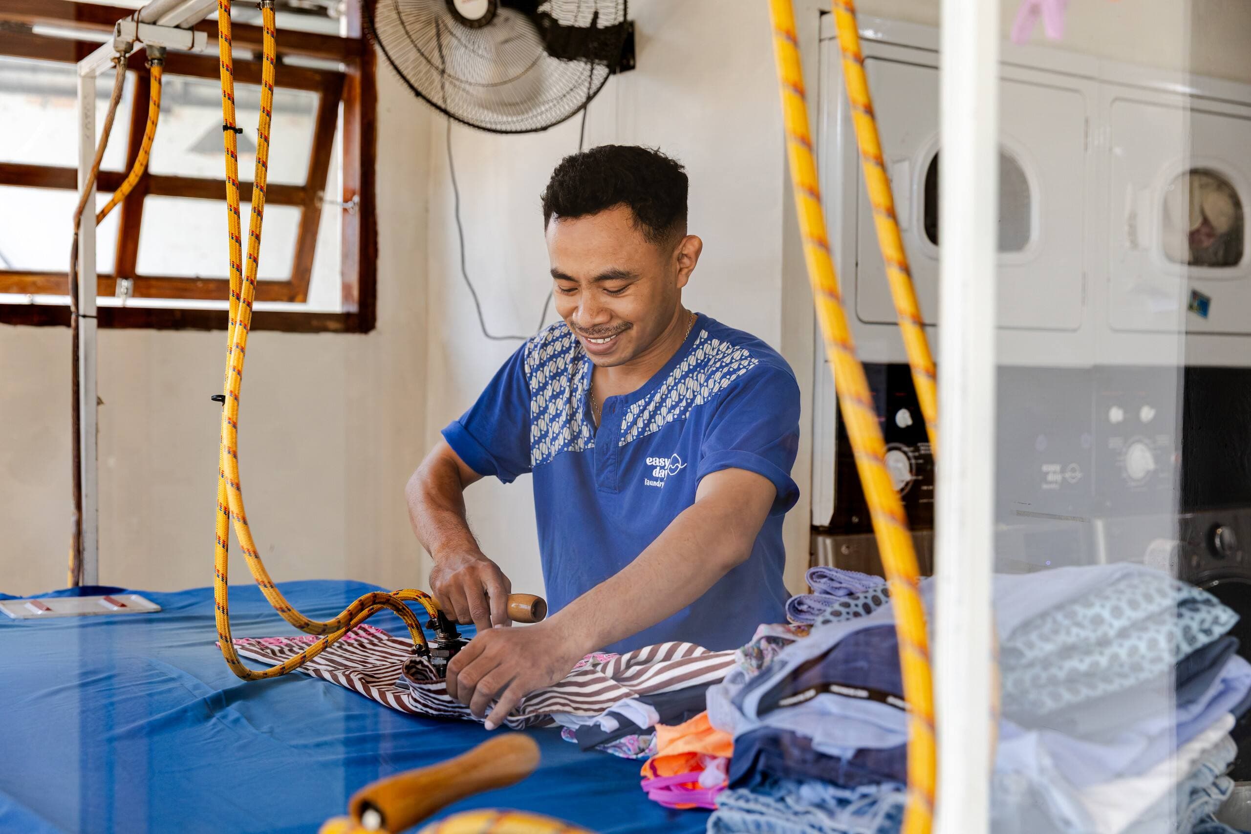Easy Day Laundry team member steam-pressing clothes at the ironing station