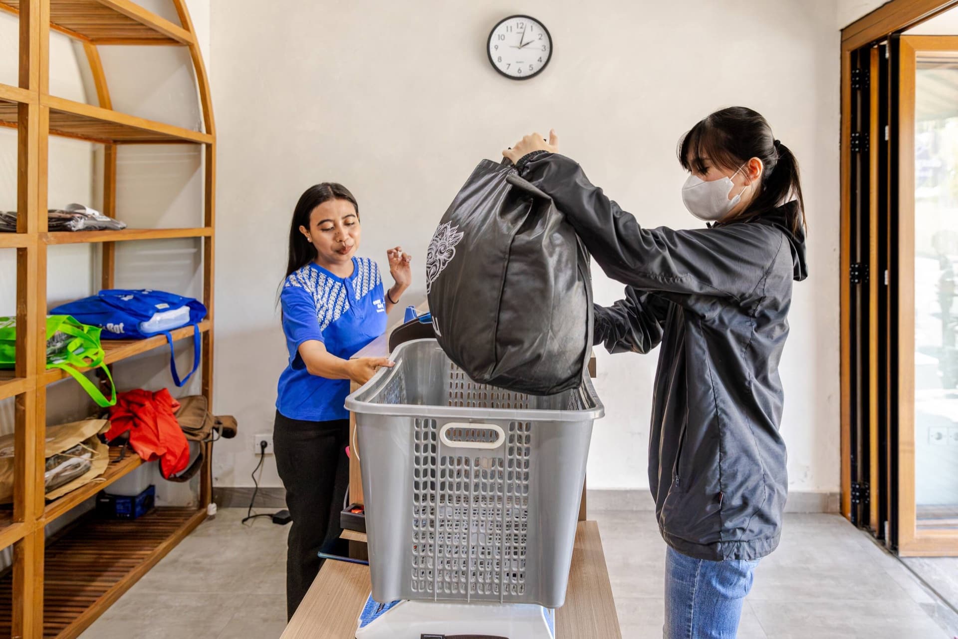 Customer dropping a laundry bag into the weighing basket at an Easy Day Laundry shop counter in Bali