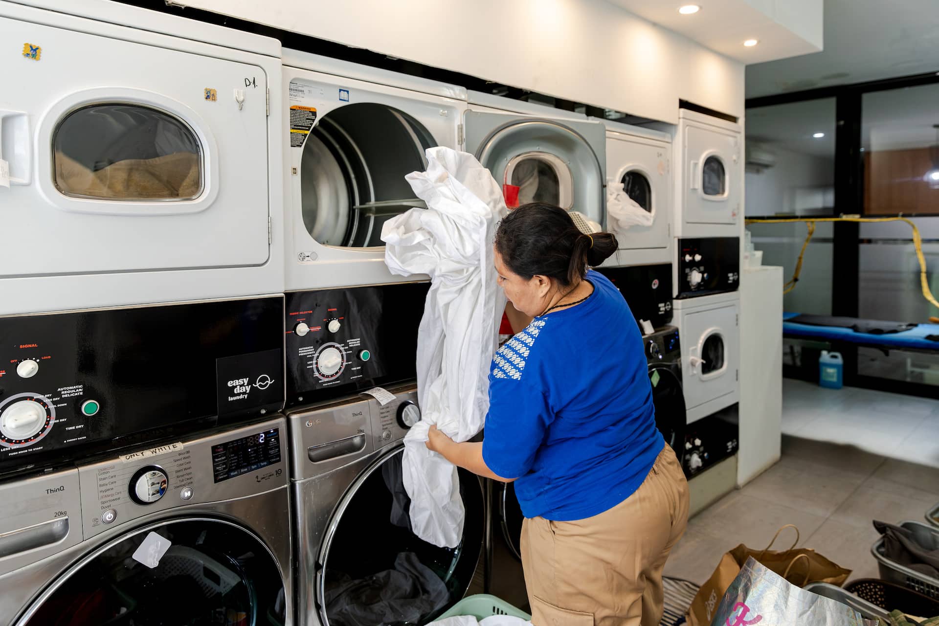Easy Day Laundry team member loading white linens into a machine for a bulk order