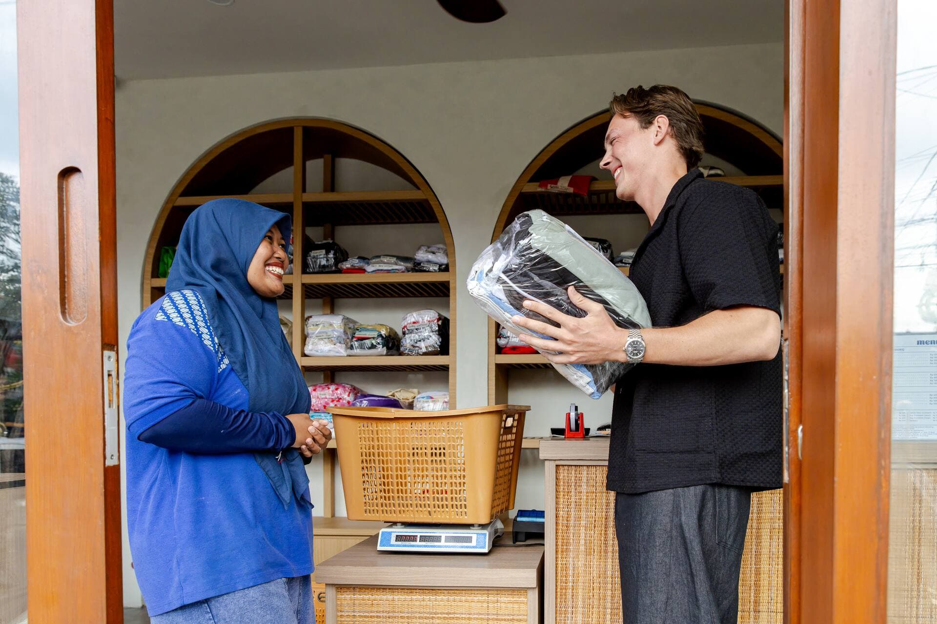 Easy Day Laundry team member handing a packed laundry order to a customer at the Pererenan counter